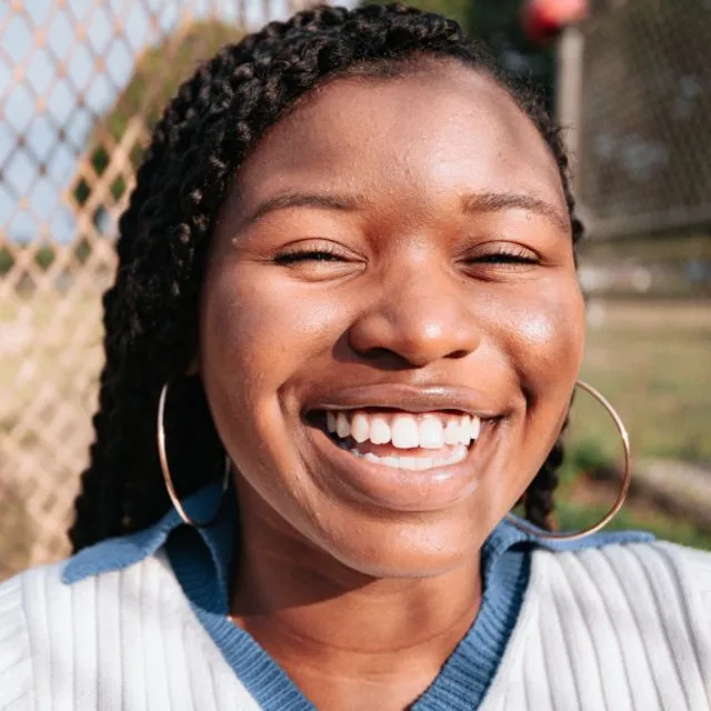 Une jeune femme éclate d’un grand sourire