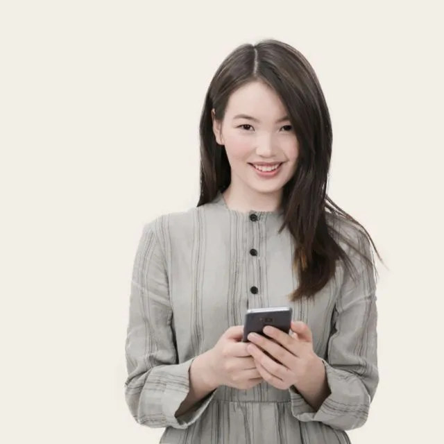 A young woman smiles as she looks at her phone